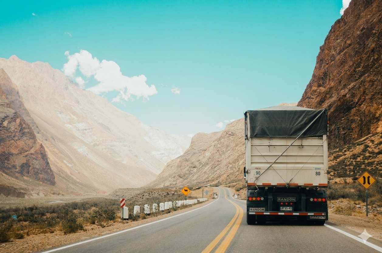 Heavy-duty freight truck driving on an open road under clear daylight
